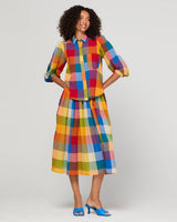Woman wearing a colorful checkered outfit on a plain background