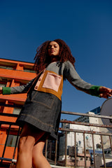 Woman wearing a denim tunic dress standing on a rooftop with a cityscape background