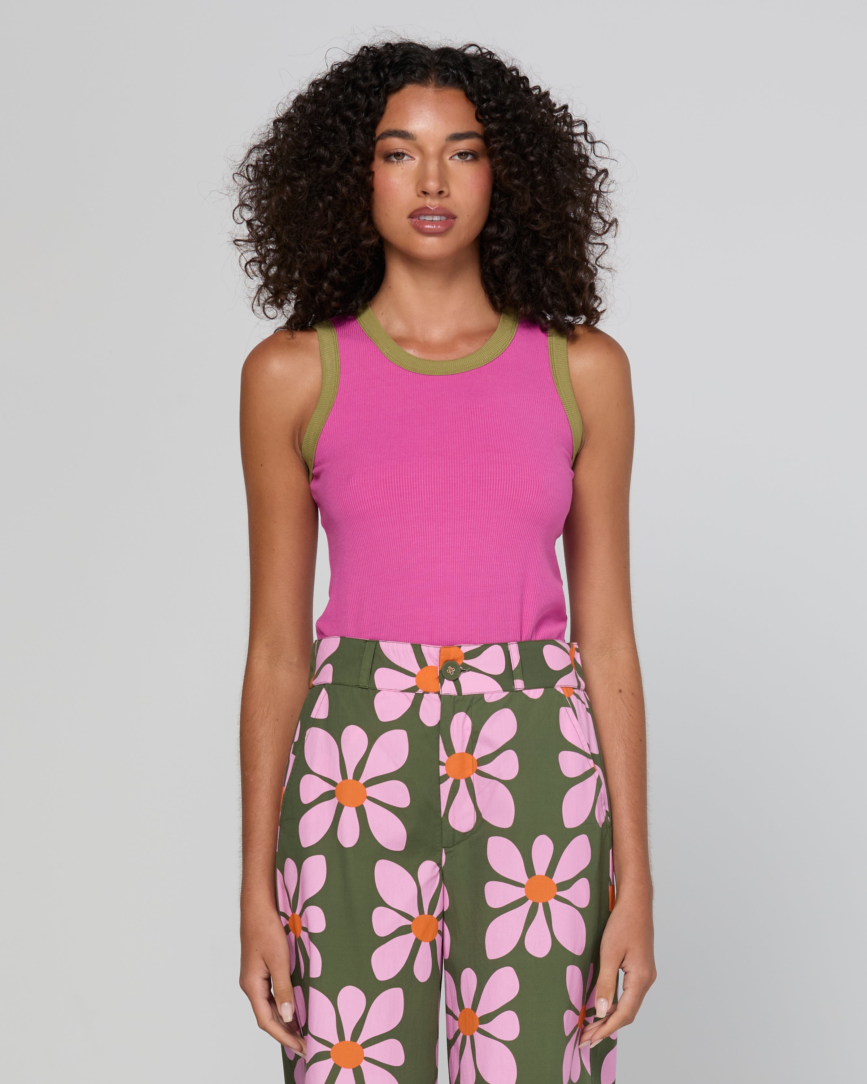 Woman wearing a pink top and green floral skirt on a plain background