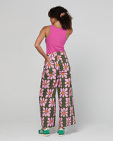 Person wearing a pink sleeveless top and floral pants on a white background