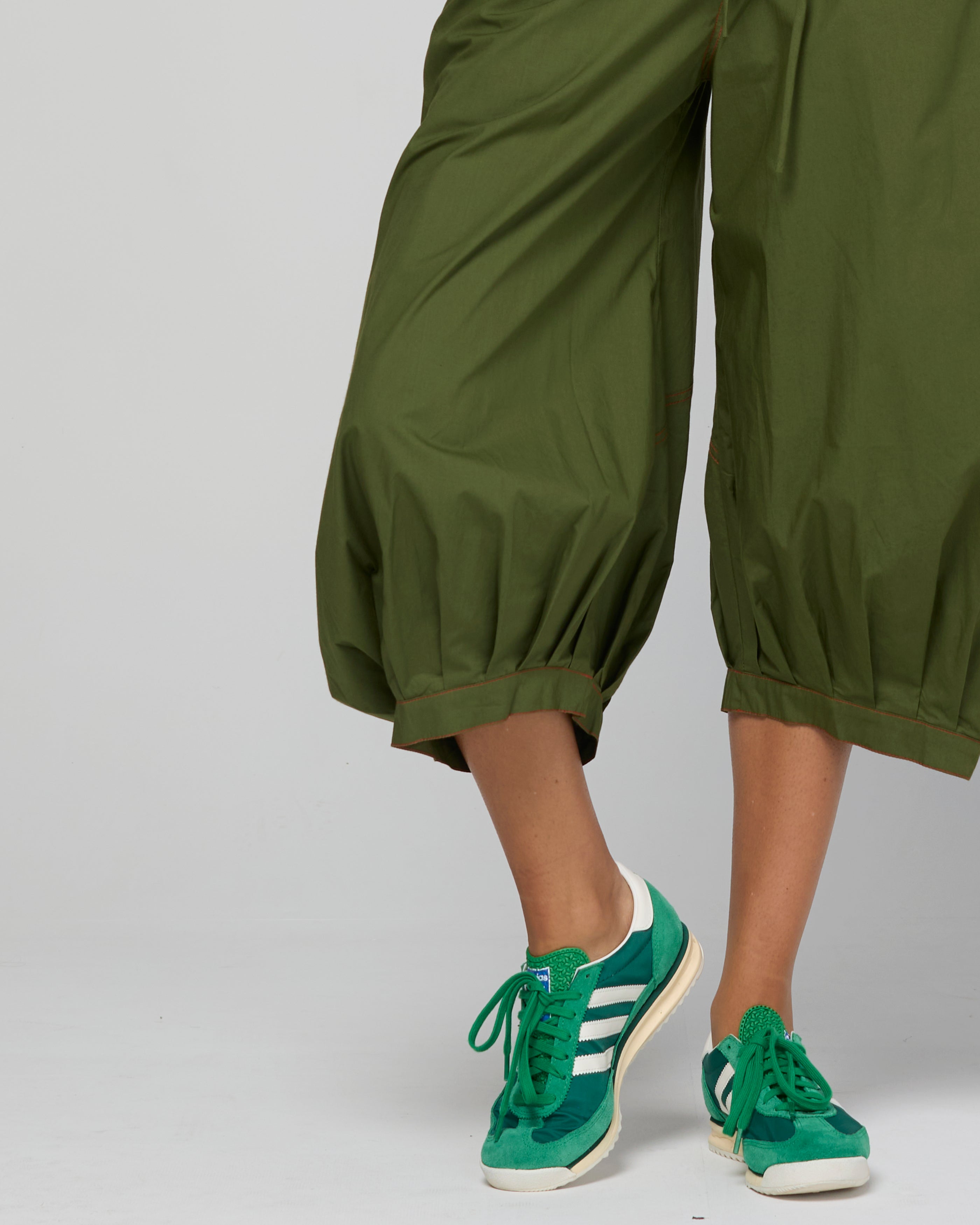 Green guru pants with  green sneakers on a plain background