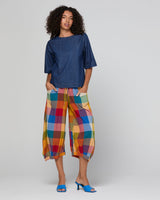 Woman wearing a blue top and colorful plaid pants on a white background