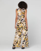 A model viewed from the back wearing a sleeveless top and wide-leg pant with a bold yellow, black, and white paisley pattern, set against a plain light gray studio background.