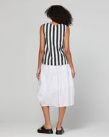 A woman shown from the back wearing a sleeveless black and white vertically striped top paired with a white midi skirt and black platform sandals, against a light gray studio background.