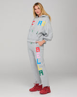 Person wearing a gray tracksuit set with colorful letters on a plain background