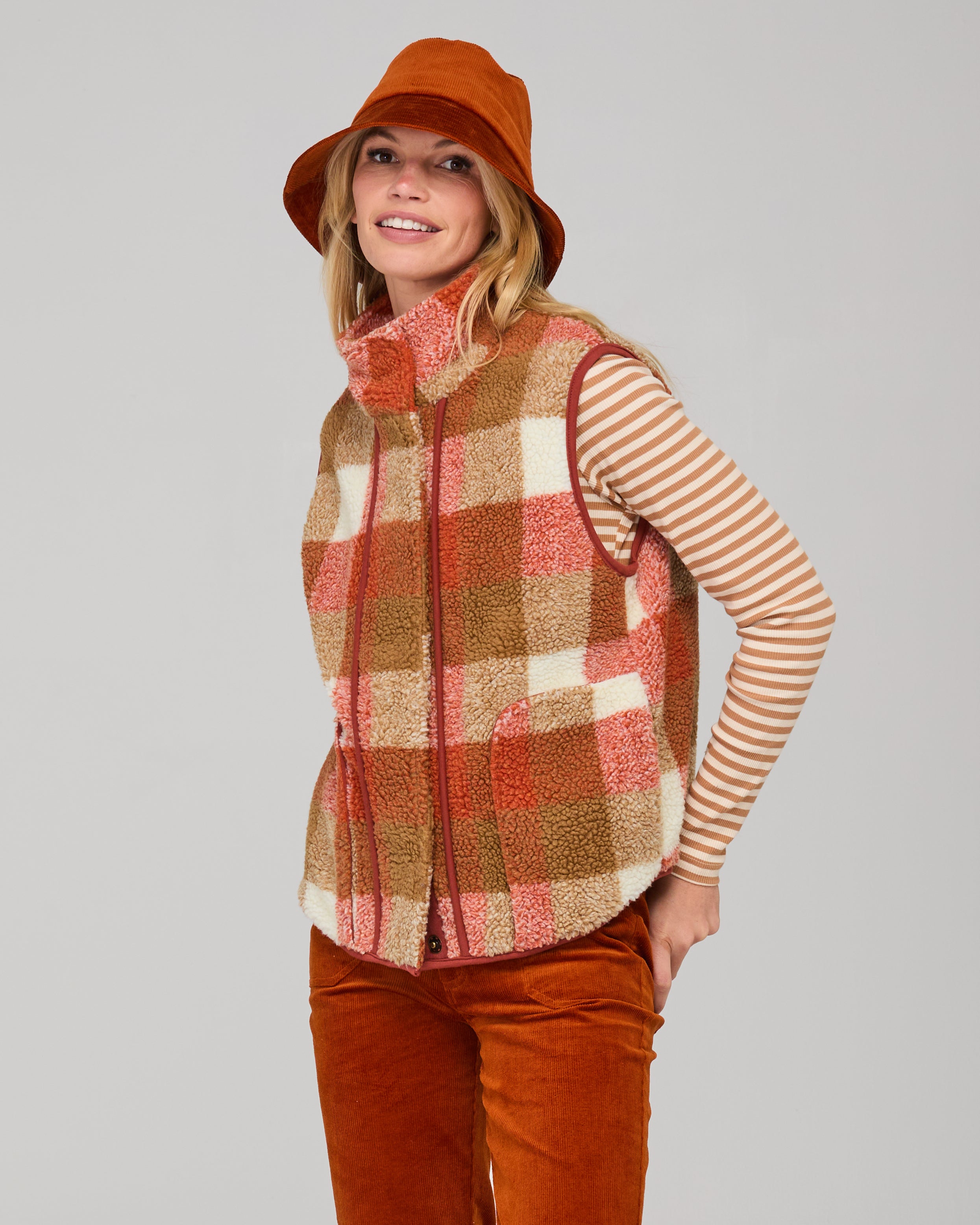 Woman wearing a rust-colored orange corduroy hat on a gray background