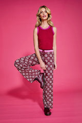 Woman wearing a red top and patterned knitted pants on a pink background