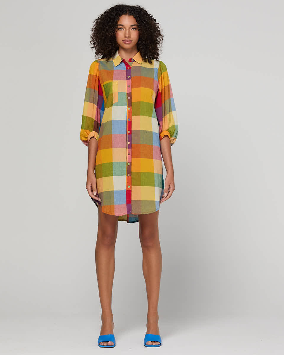 Woman wearing a colorful checkered dress on a plain background