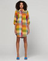 Woman wearing a colorful checkered dress on a plain background