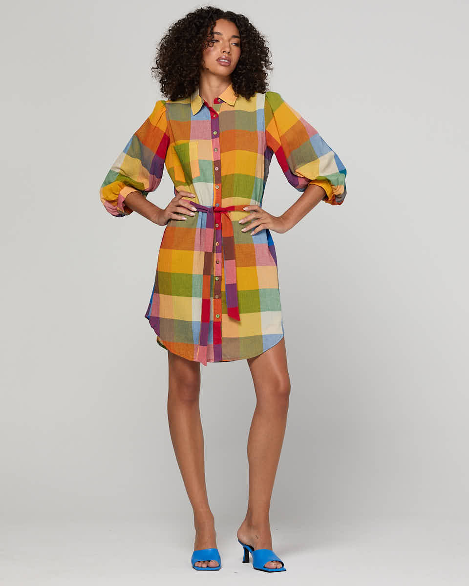 Woman wearing a colorful checkered shirt dress on a plain background