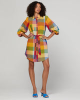 Woman wearing a colorful checkered shirt dress on a plain background