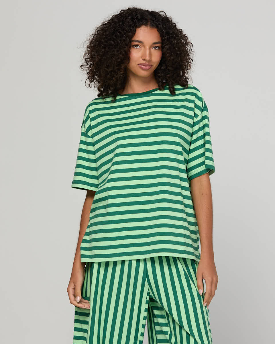 Woman wearing a green striped top on a gray background
