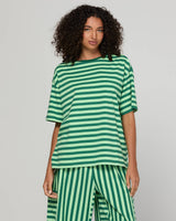 Woman wearing a green striped top on a gray background